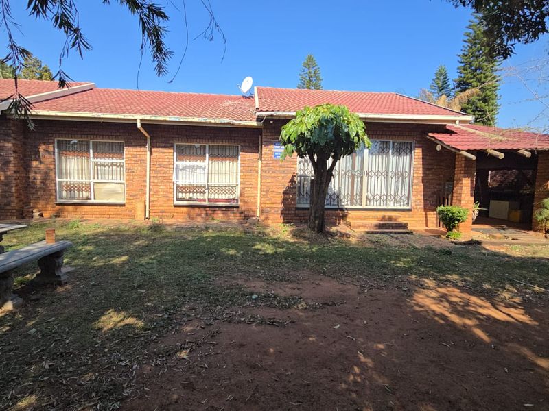 Rear view of a brick house featuring a tiled roof, sliding glass doors with security gates, and a covered patio area overlooking the garden.