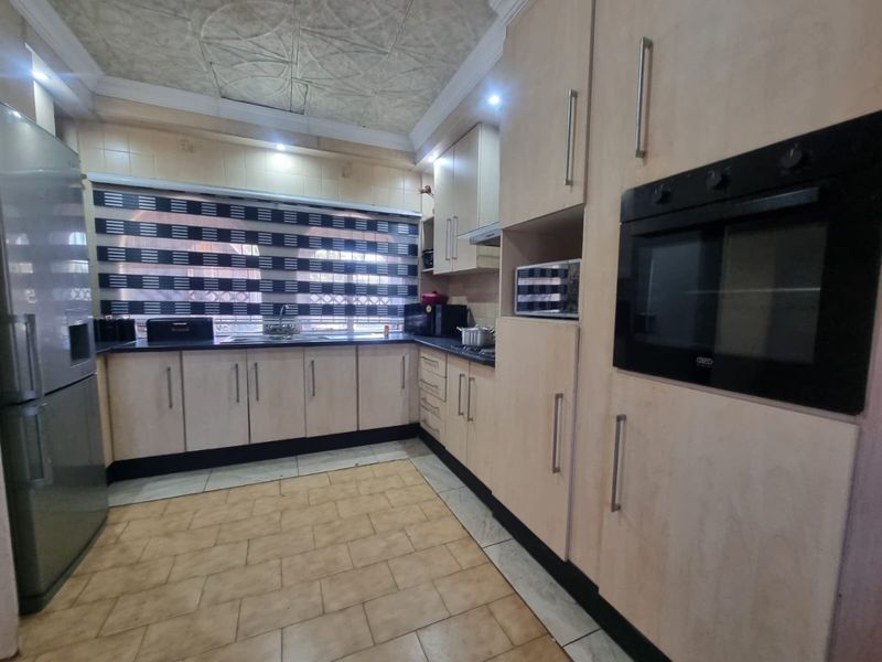 A functional kitchen featuring light-toned built-in cabinetry, integrated oven, dark countertops, and tiled flooring with a textured ceiling finish.