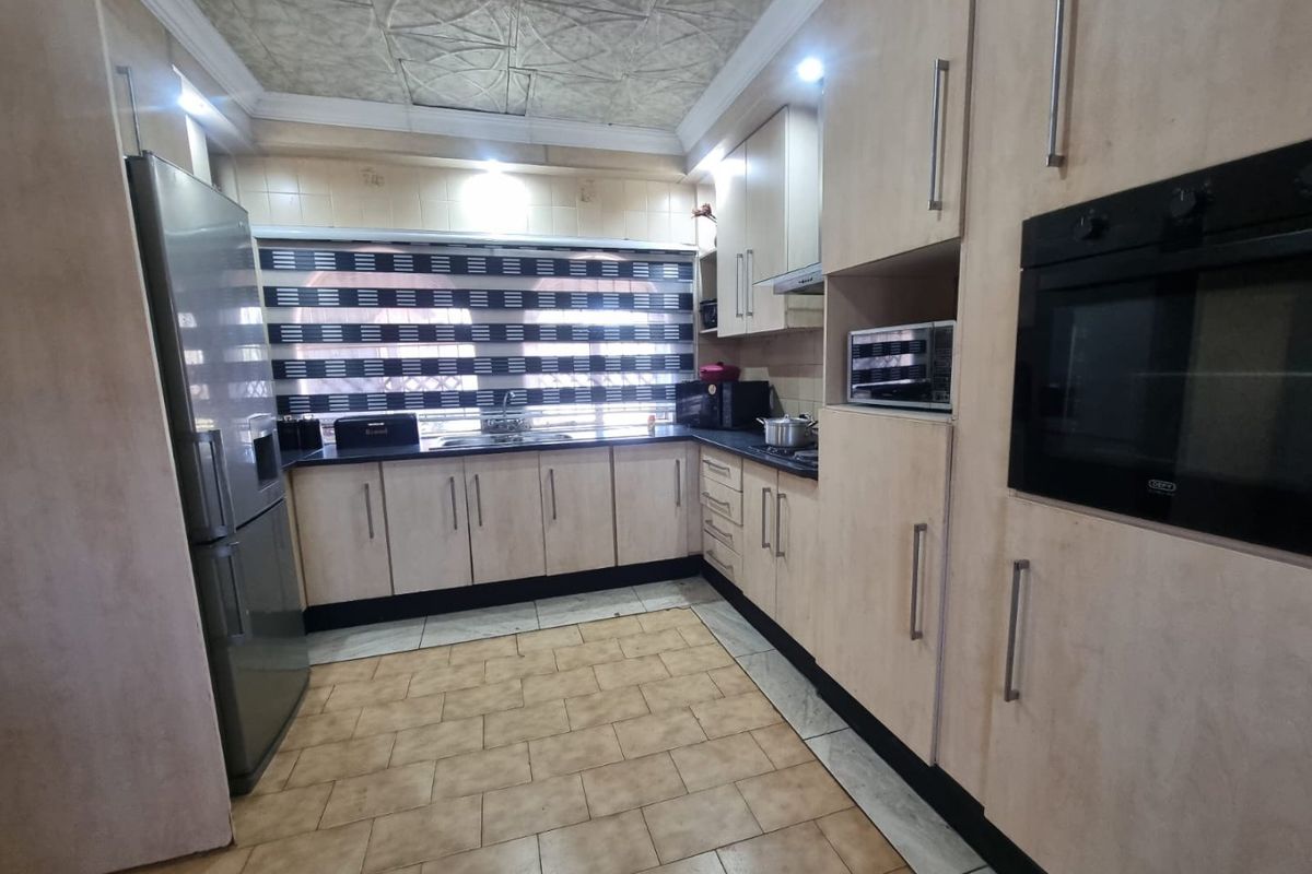 A functional kitchen featuring built-in cabinetry, integrated oven, and tiled flooring, offering a practical layout with ample storage space.