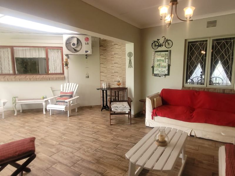 Spacious living area featuring tiled flooring, an integrated air conditioning unit, and large windows with security bars, offering a comfortable and functional layout.