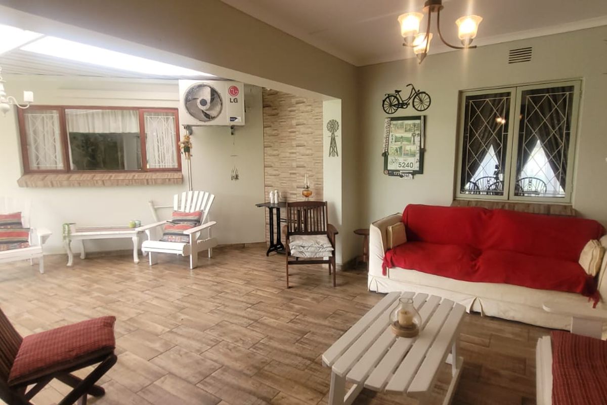 Spacious living area featuring tiled flooring, an integrated air conditioning unit, and large windows with security bars, offering a comfortable and functional layout.