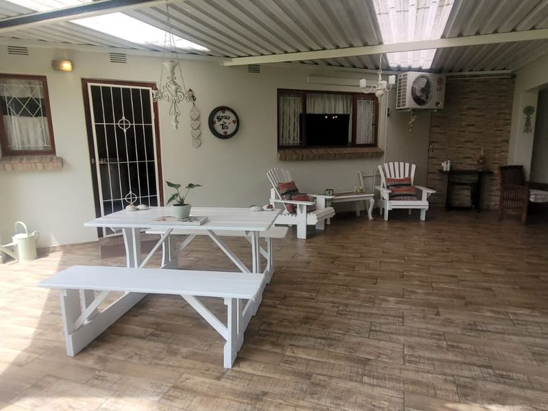 A spacious covered patio featuring wood-look tiled flooring, a stone accent wall, and an integrated air conditioning unit, ideal for outdoor entertaining.