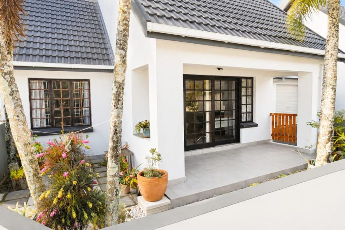 A well-maintained townhouse rear exterior featuring a covered patio, tiled flooring, and classic french doors leading into the home.