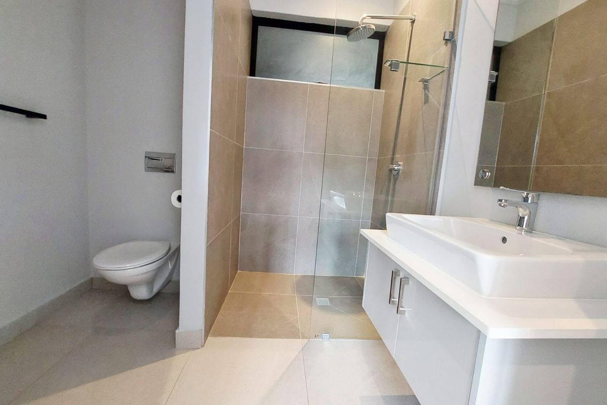 Modern bathroom featuring a wall-mounted toilet, a glass-enclosed walk-in shower with neutral tiling, and a contemporary vanity with a vessel sink.