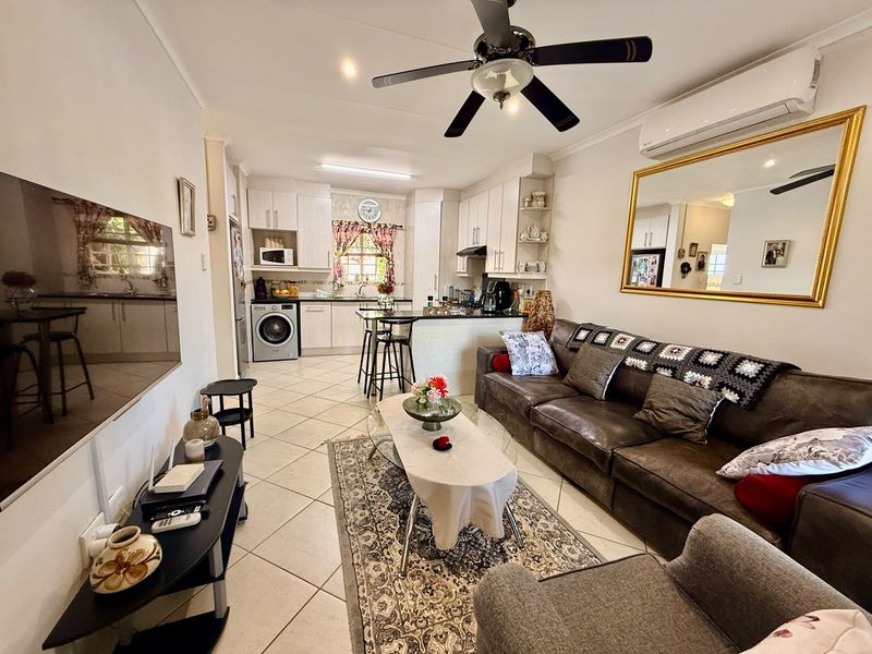Open-plan living and kitchen area featuring tiled floors, a central kitchen island, built-in cabinetry, and integrated air conditioning.