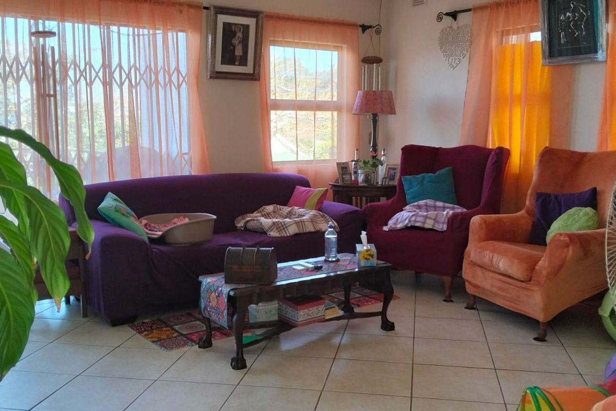 A living room featuring ceramic floor tiles, a decorative ceiling rose with a pendant light, and security gates on the windows.