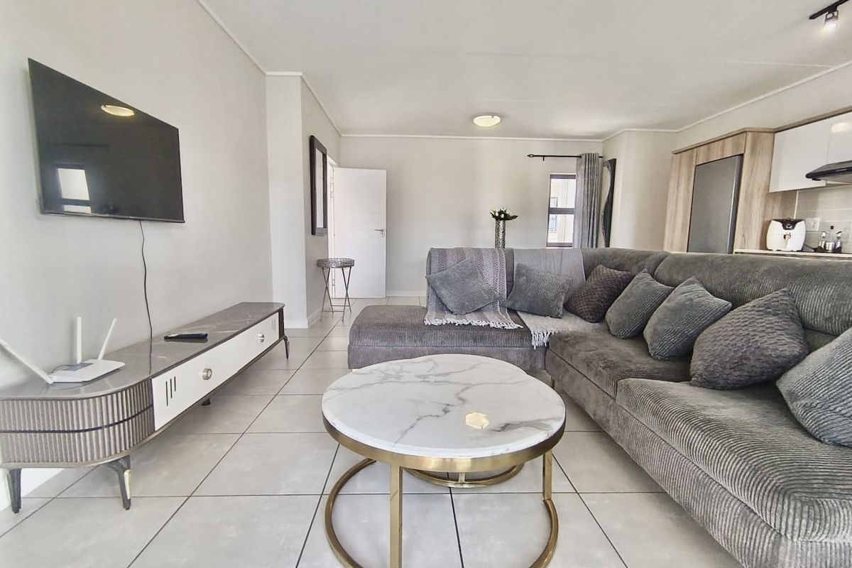 An open-plan living area featuring neutral tiled flooring, a modern kitchen with built-in cabinetry, and a spacious layout suitable for comfortable living.
