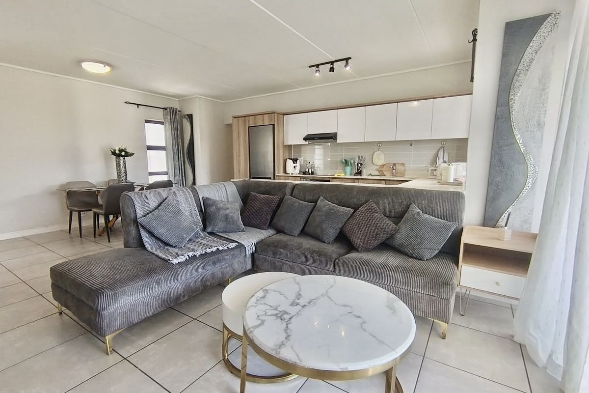 Open-plan living area featuring a modern kitchen with sleek cabinetry, tiled flooring throughout, and a bright, functional layout suitable for contemporary apartment living.
