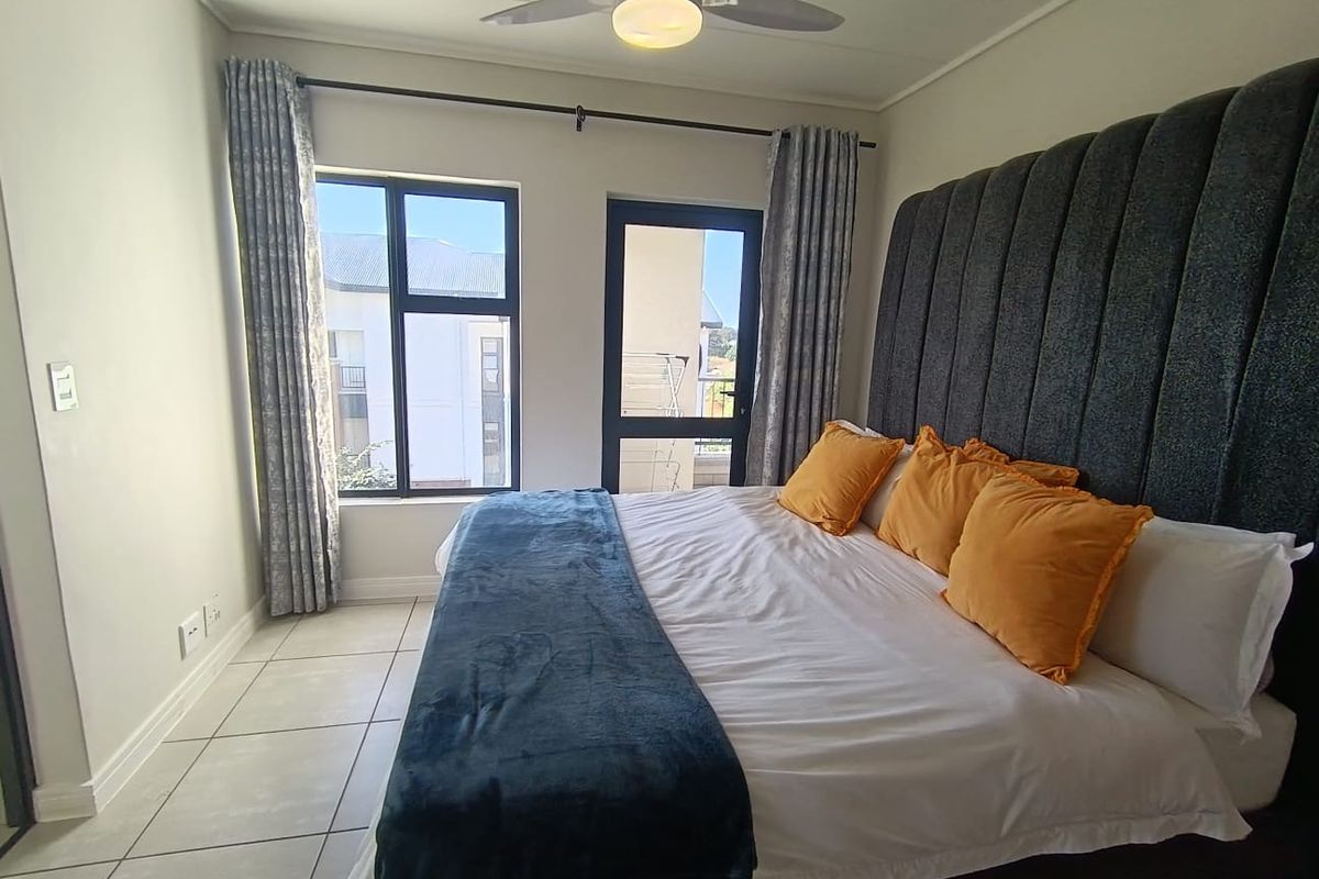 A well-maintained bedroom featuring tiled flooring, a ceiling fan, and direct access to an outdoor area through an aluminium door.