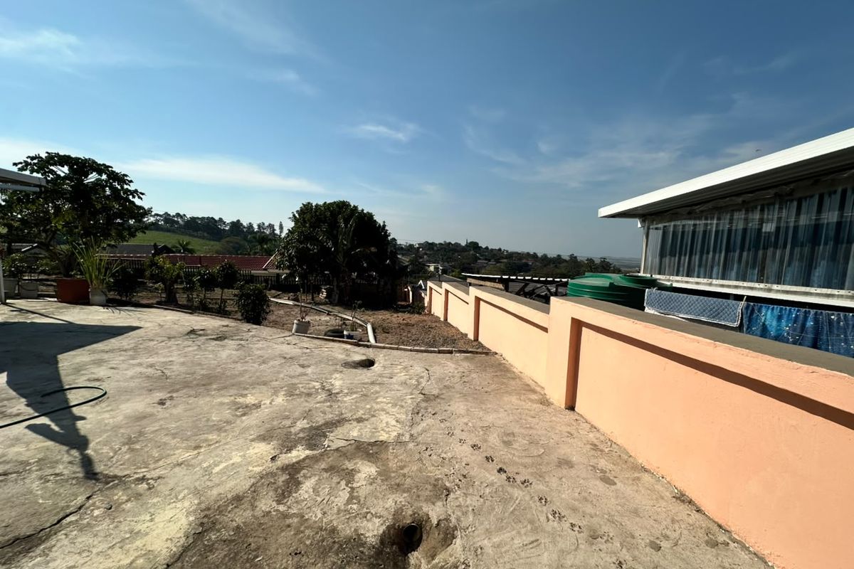 Rear outdoor area featuring a concrete patio, boundary wall, and water storage tank with views of the surrounding landscape.
