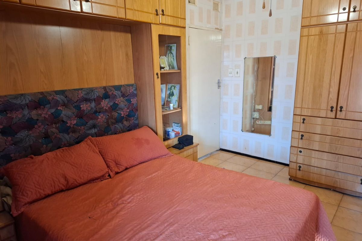 Bedroom featuring extensive built-in wooden cabinetry and integrated headboard storage, finished with tiled flooring and dated wall tiles.