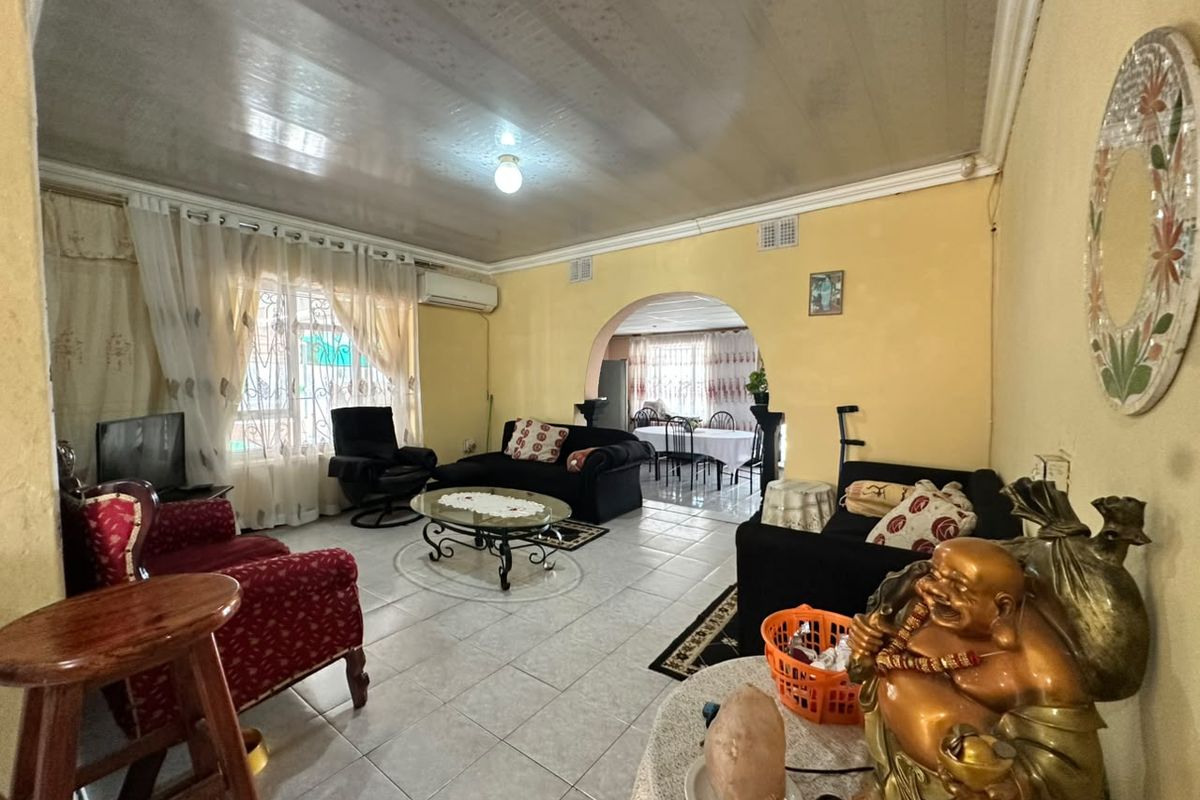 Spacious living room featuring tiled flooring, an arched entryway leading to the dining area, and a wall-mounted air conditioning unit.