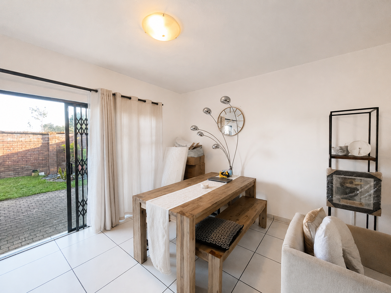 Dining area featuring tiled flooring and a sliding glass door with security gate, providing direct access to the rear patio and garden.