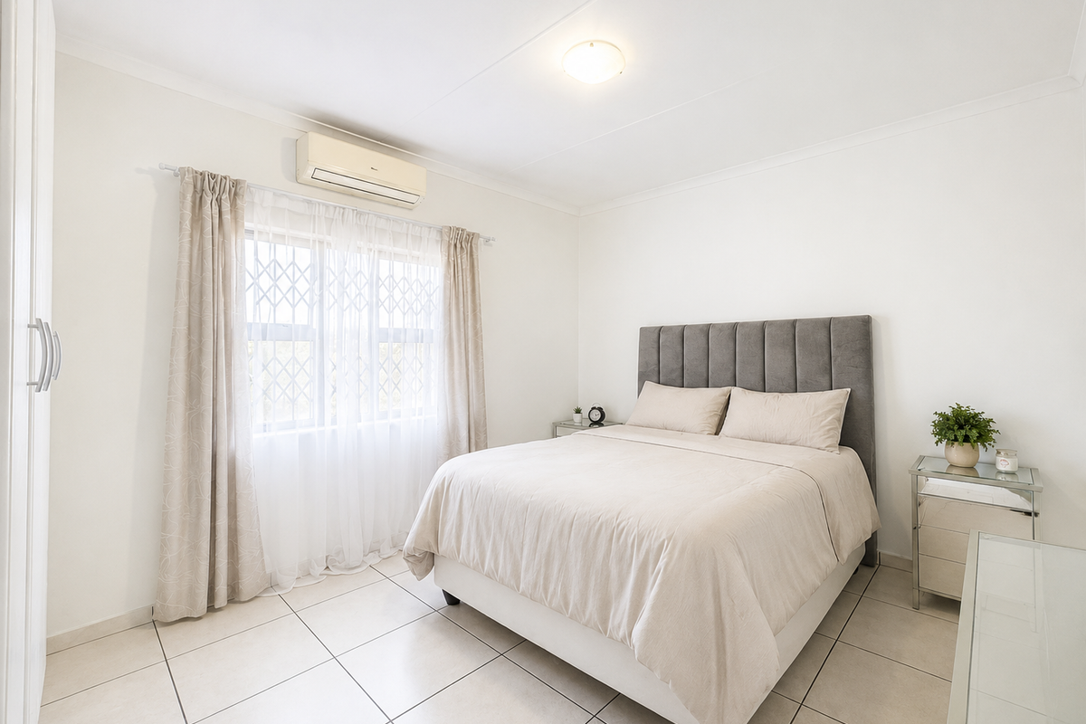 A well-maintained bedroom featuring tiled flooring, a built-in wardrobe, and a wall-mounted air conditioning unit.