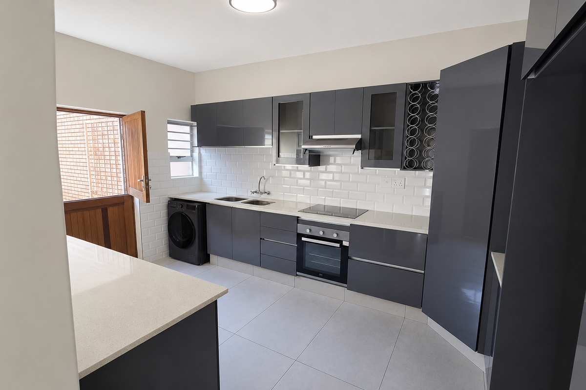Modern kitchen featuring sleek grey cabinetry, stone countertops, subway tile backsplash, integrated appliances, and direct access to an outdoor area via a stable door.