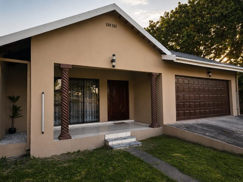 Front elevation of a single-story house featuring a covered porch with decorative columns, a double garage, and a concrete driveway.