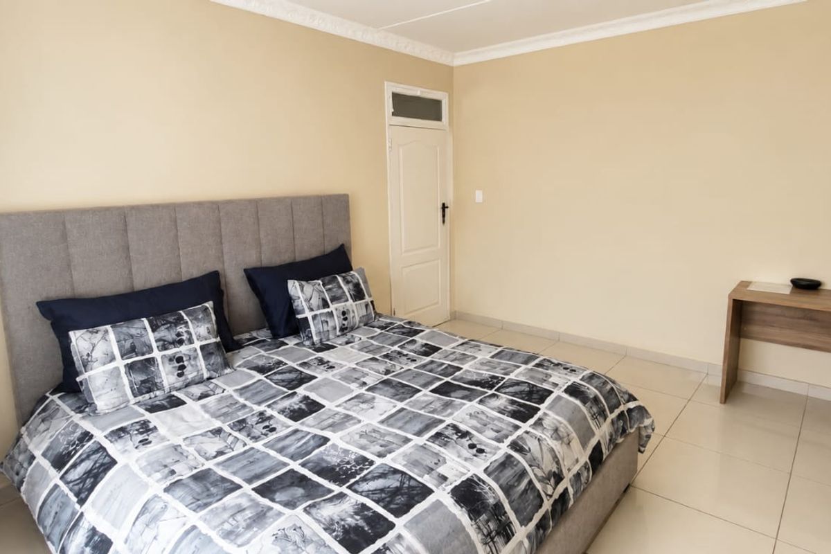 A well-maintained bedroom featuring neutral wall tones, tiled flooring, and decorative ceiling cornicing.