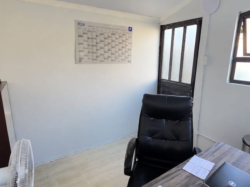 A functional home office space featuring a window and access door, providing a quiet area suitable for work or study.