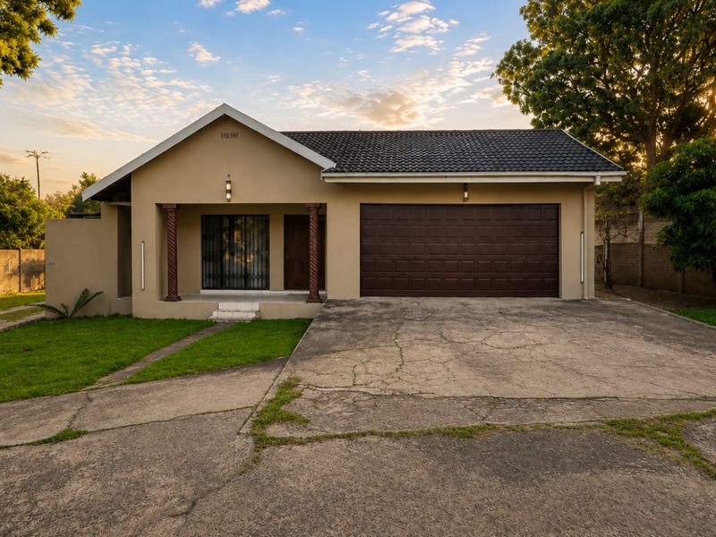 Front elevation of a single-story house featuring a tiled roof, covered porch with decorative columns, and an integrated double garage with a concrete driveway.
