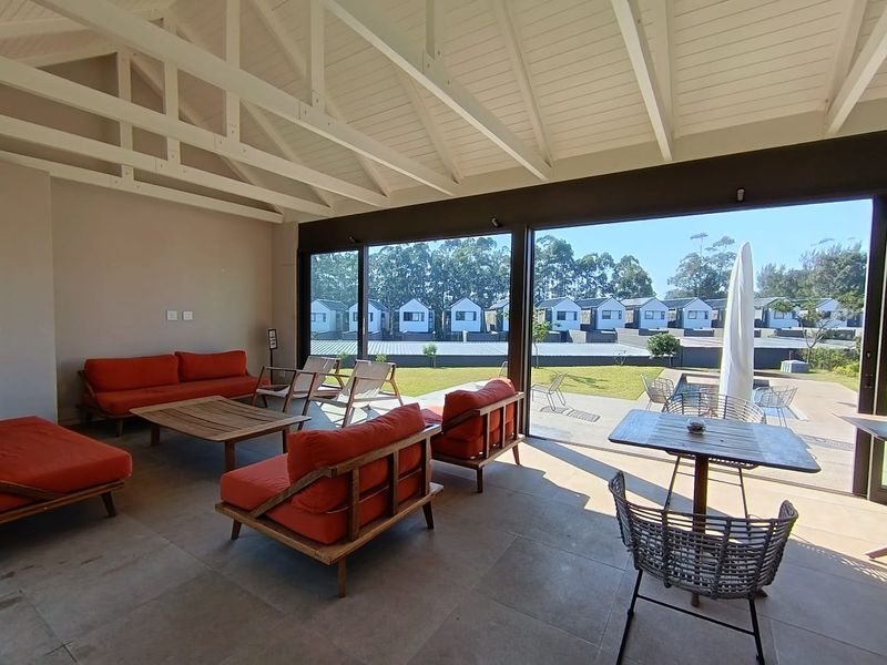 Spacious covered patio featuring exposed timber rafters, large format floor tiles, and expansive sliding glass doors opening to the garden and pool area.