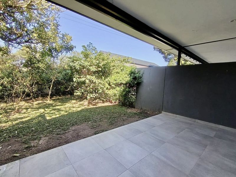 A covered patio area featuring modern tiled flooring and a private garden view, providing a seamless transition between indoor and outdoor living spaces.