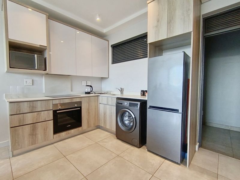 Modern kitchen featuring sleek cabinetry, stone countertops, integrated appliances, and tiled flooring, offering a clean and functional culinary space.