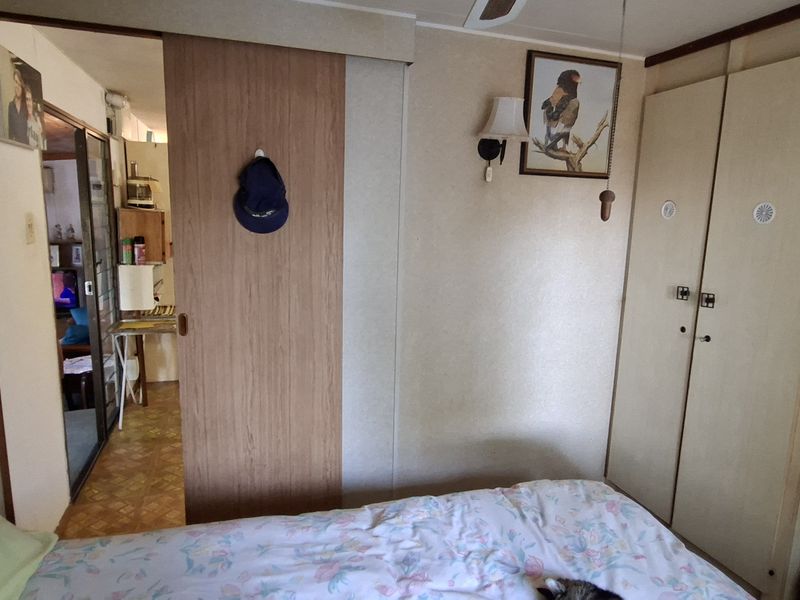 A bedroom featuring built-in wardrobes and a sliding door leading to an adjacent living space.