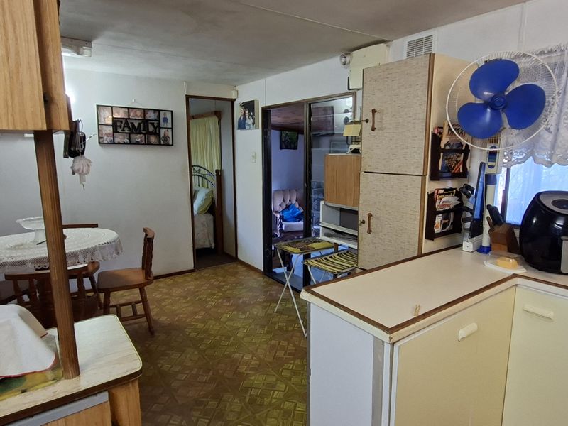 Open plan kitchen and dining area featuring dated laminate cabinetry, vinyl flooring, and direct access to an adjacent room through a sliding glass door.
