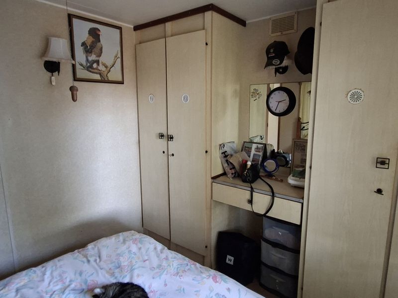 A bedroom featuring built-in wardrobes and a integrated vanity unit with dated cabinetry finishes.