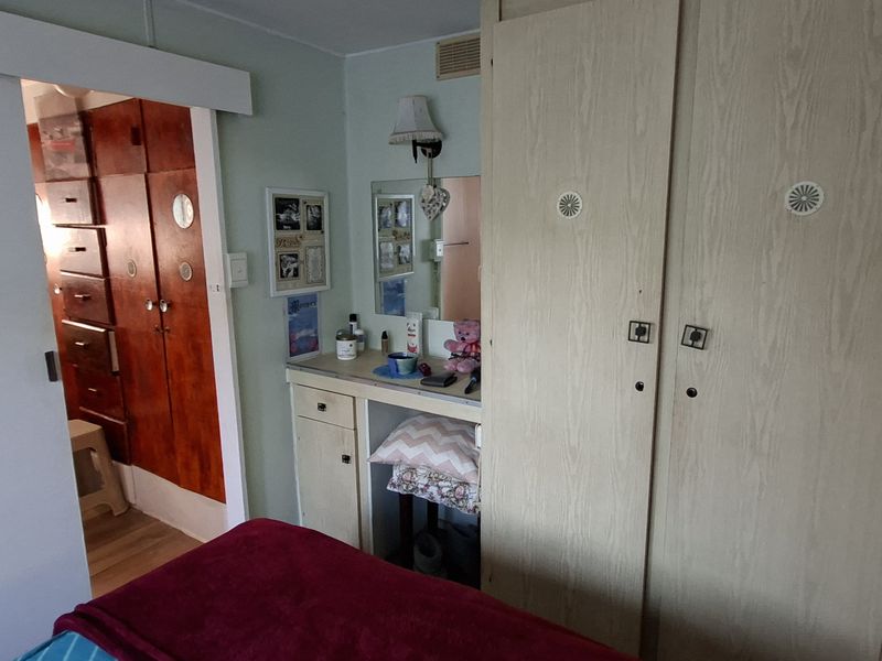 Bedroom featuring built-in wardrobes and a vanity unit, with a sliding door leading to an adjacent room.