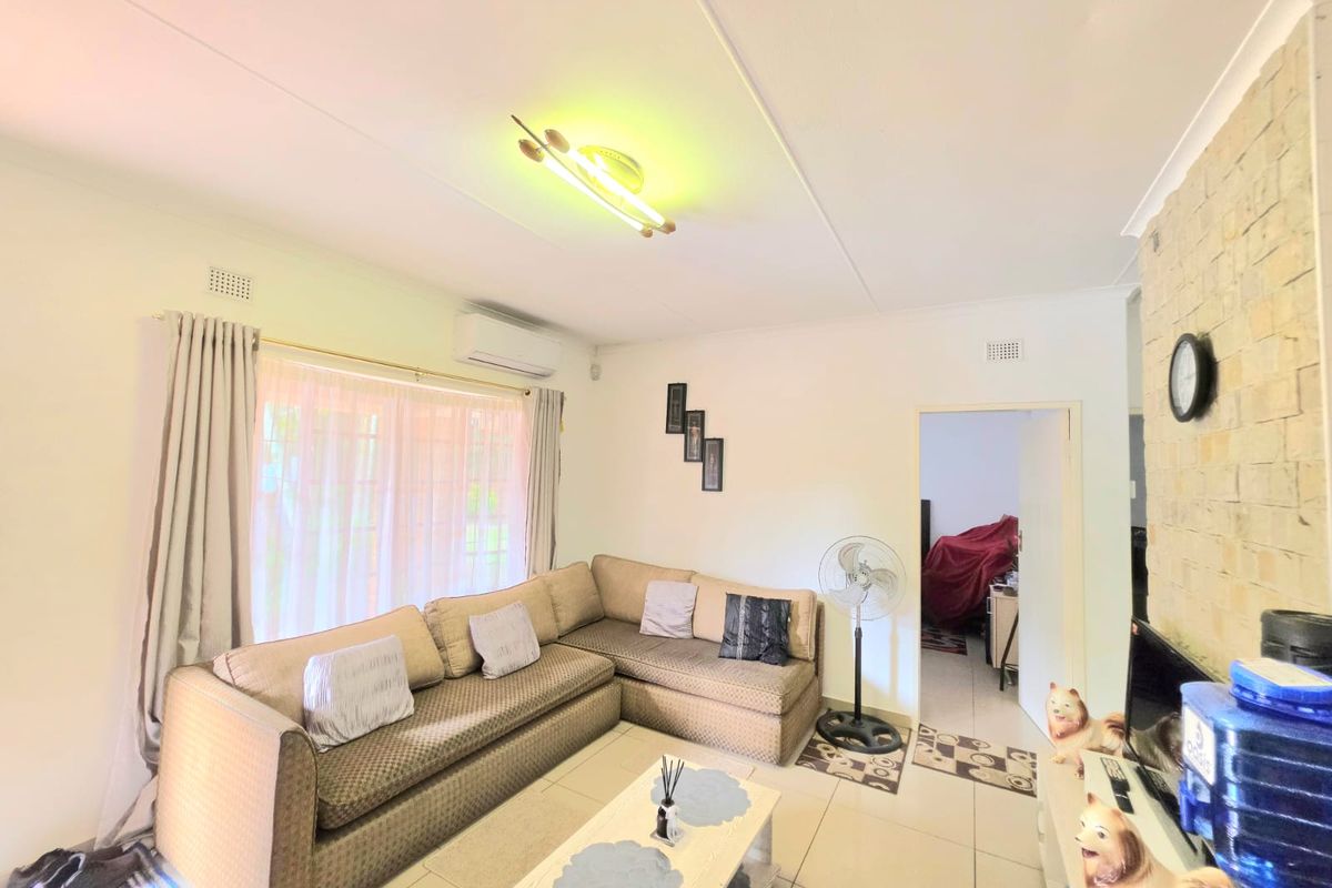 A living room featuring tiled flooring, a stone accent wall, and a wall-mounted split-system air conditioner.