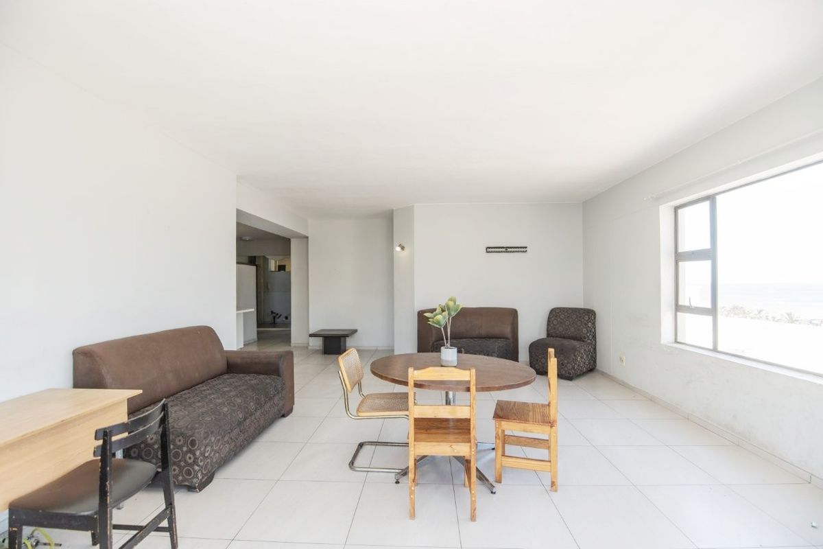 Spacious open-plan living and dining area featuring neutral tiled flooring and large windows providing ample natural light.