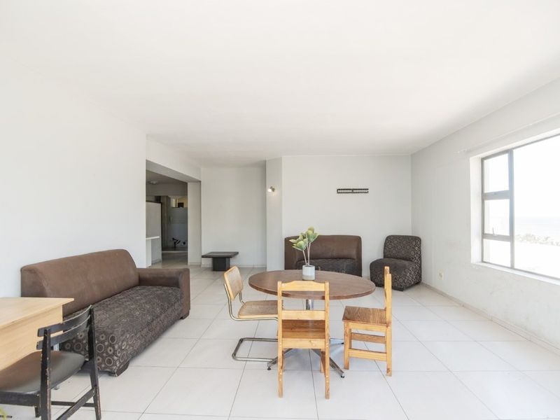 Spacious open-plan living and dining area featuring neutral tiled flooring and large windows providing ample natural light.