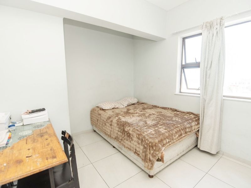 A functional bedroom featuring tiled flooring and a large window that allows for natural light.