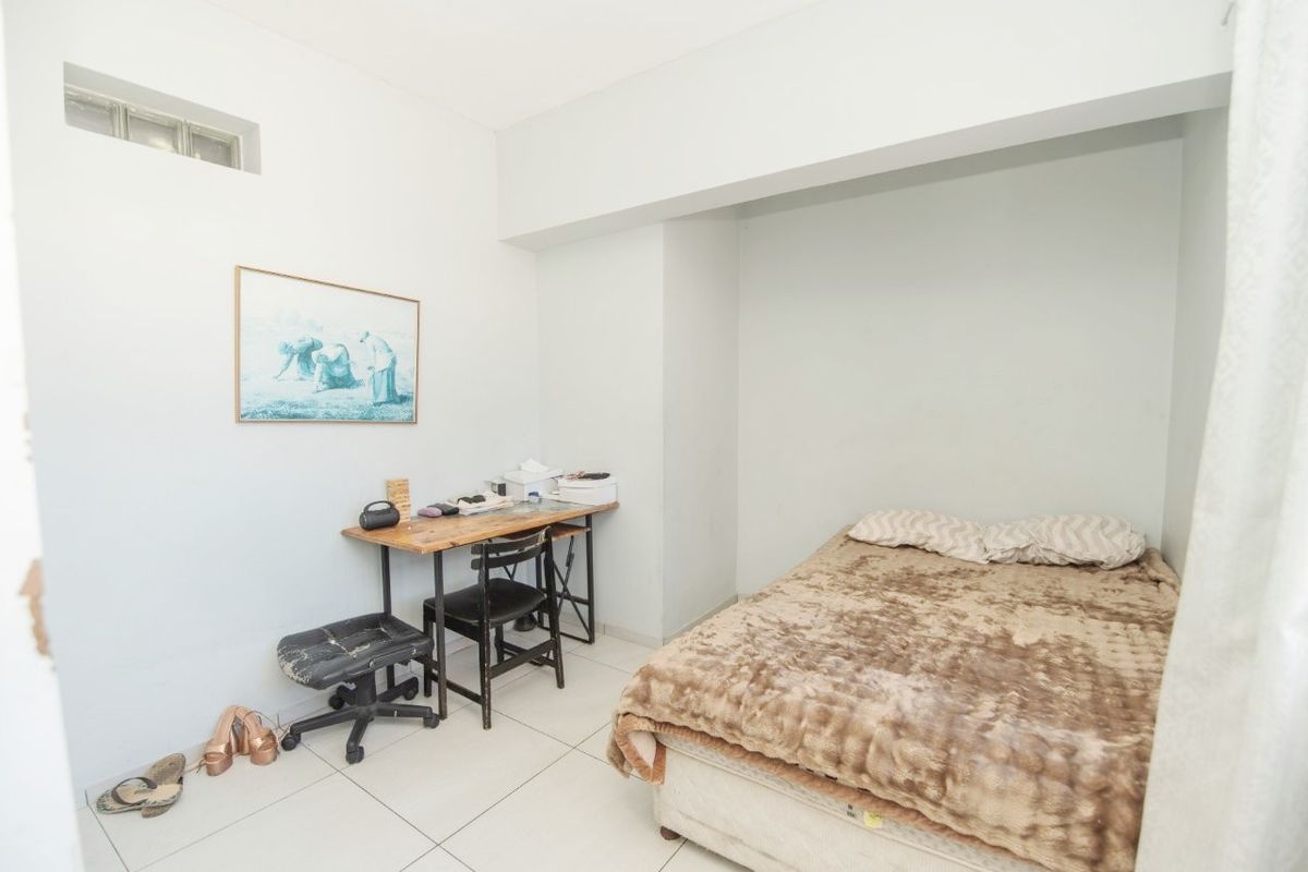 A functional bedroom featuring tiled flooring and a high-level clerestory window, providing a simple and practical living space.
