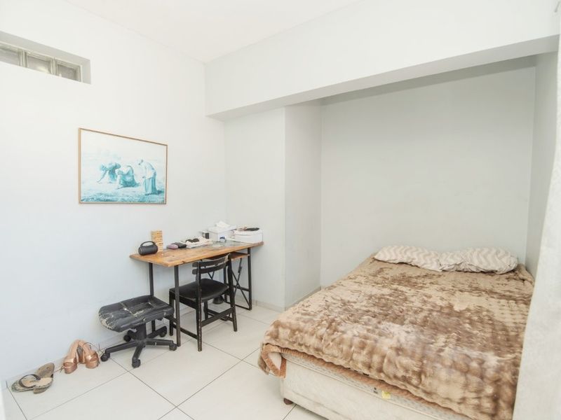 A functional bedroom featuring tiled flooring and a high-level clerestory window, providing a simple and practical living space.