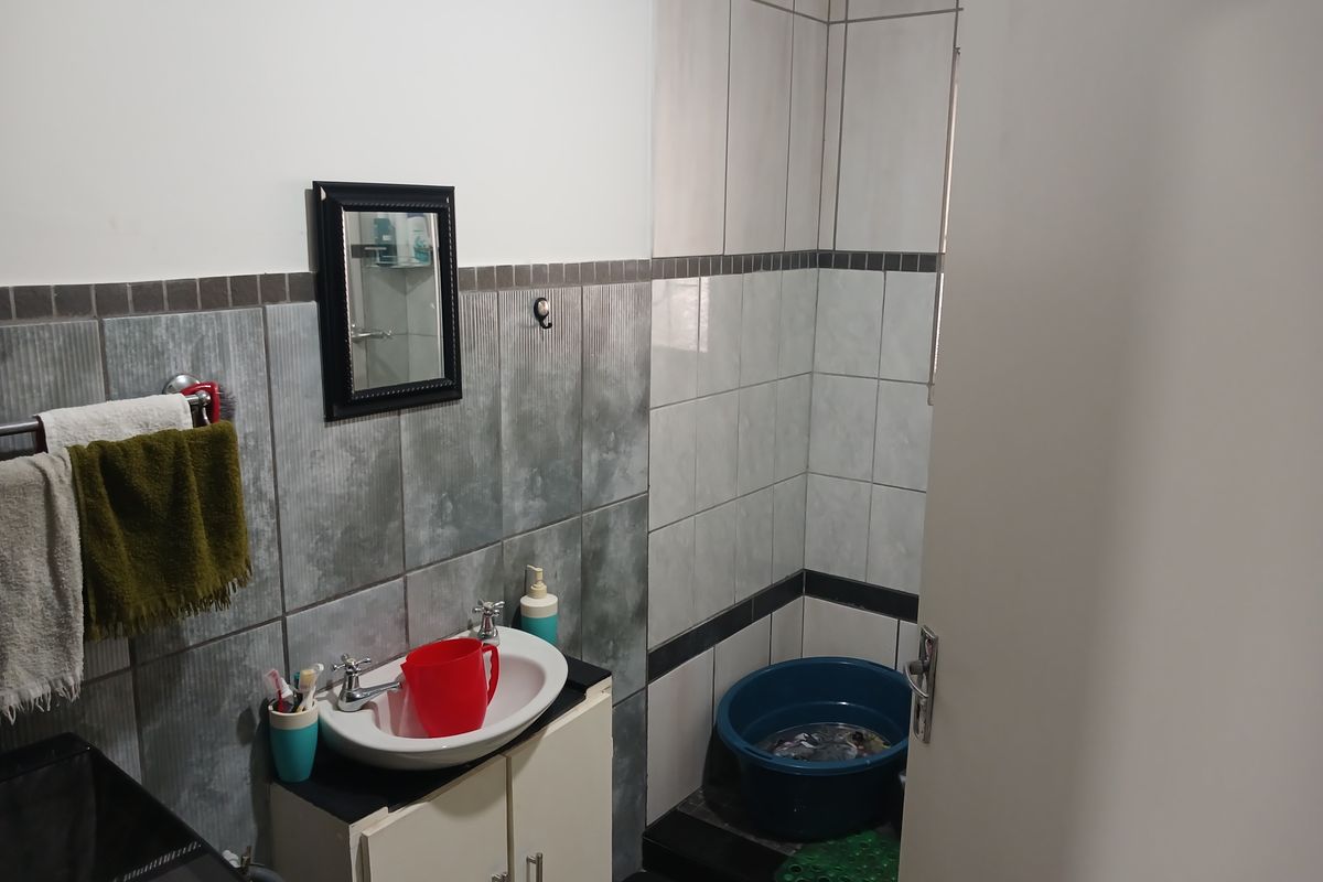 A functional bathroom featuring a vanity cabinet with a basin, wall tiling, and a dedicated shower area.