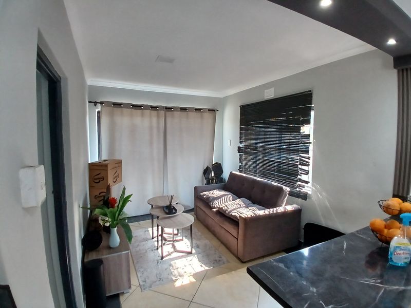 Open plan living area featuring tiled flooring, recessed lighting, and direct access to the exterior via a sliding glass door.