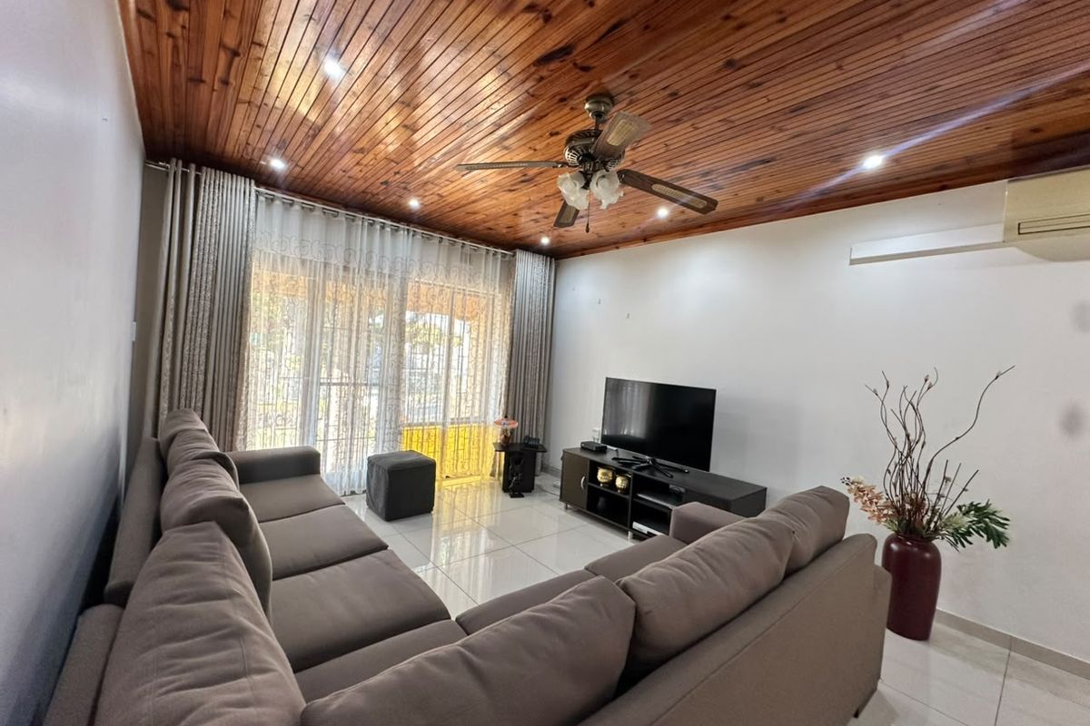 Spacious living room featuring a warm timber-paneled ceiling, tiled flooring, ceiling fan, and direct access to the outdoor area through sliding glass doors.