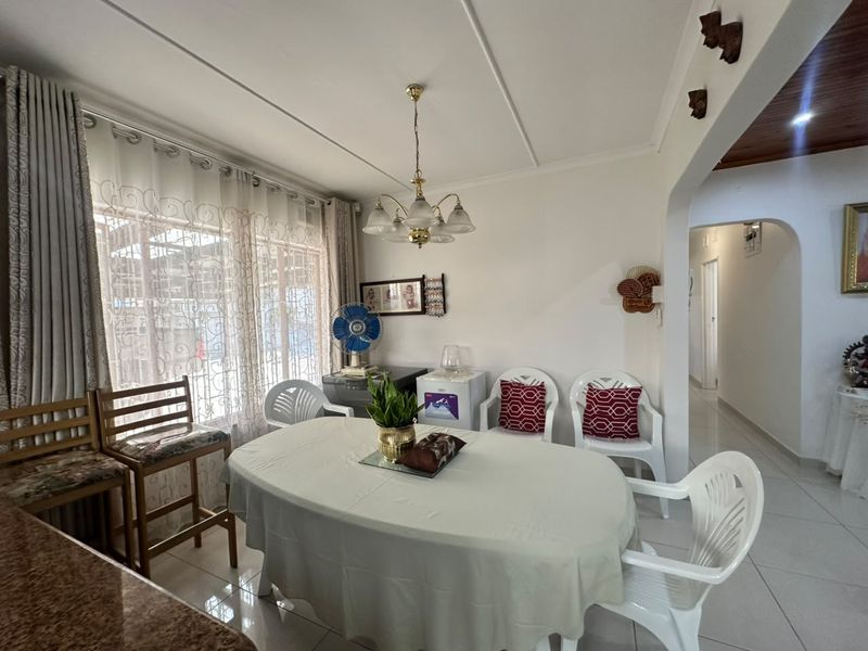 A functional dining area featuring tiled flooring, a central chandelier, and an open archway leading to the hallway.