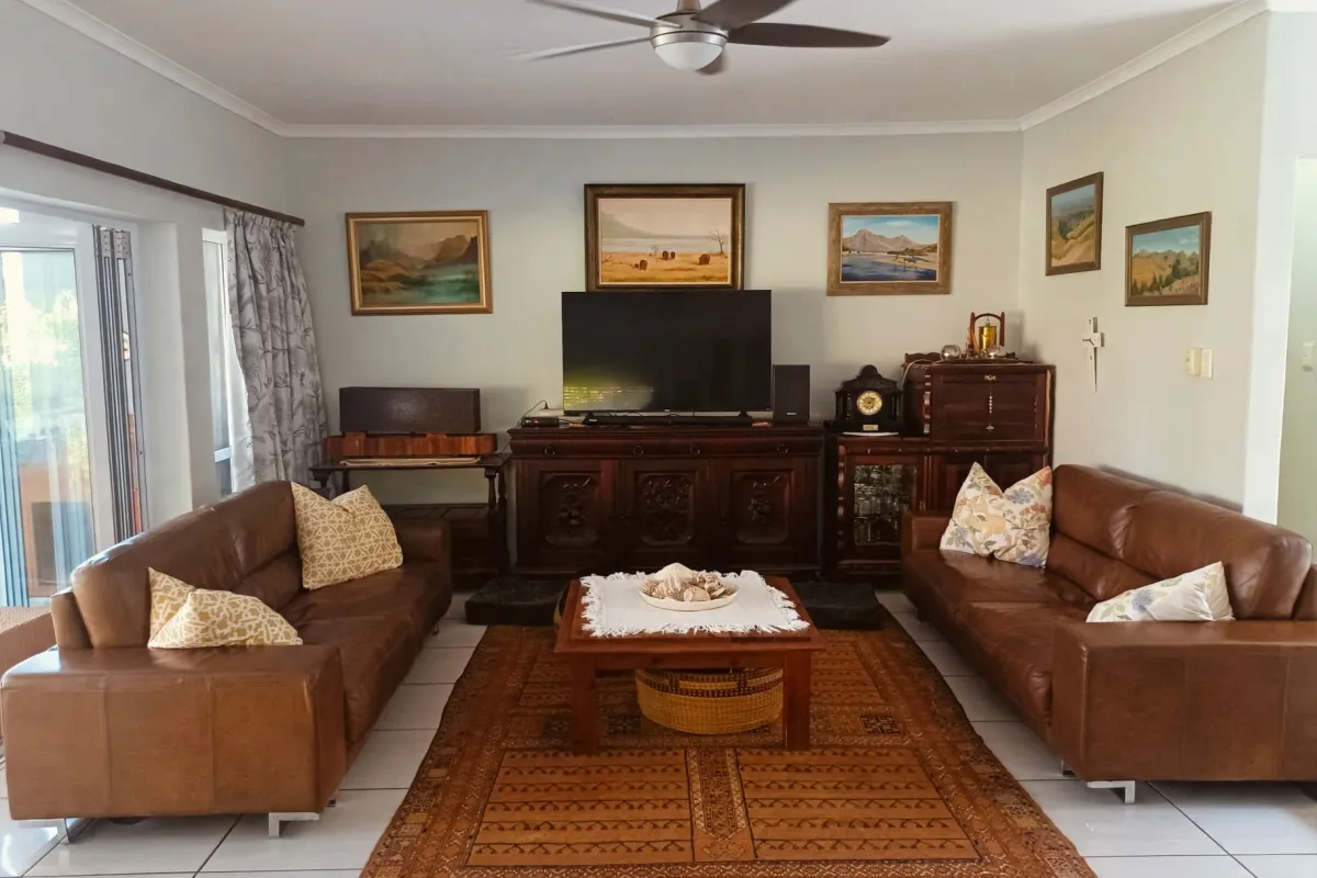 A well-maintained living room featuring tiled flooring, a central ceiling fan, and large sliding glass doors providing natural light and outdoor access.