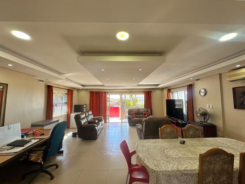 Spacious open-plan living and dining area featuring a modern drop ceiling with recessed lighting, tiled floors, and direct access to an outdoor patio.