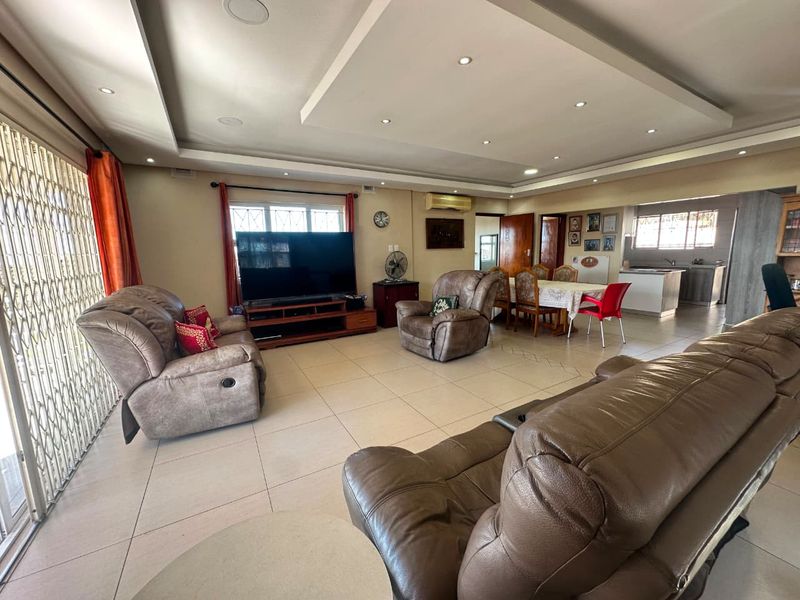 Spacious open-plan living and dining area featuring tiled floors, recessed ceiling lighting, and an integrated kitchen with modern cabinetry.