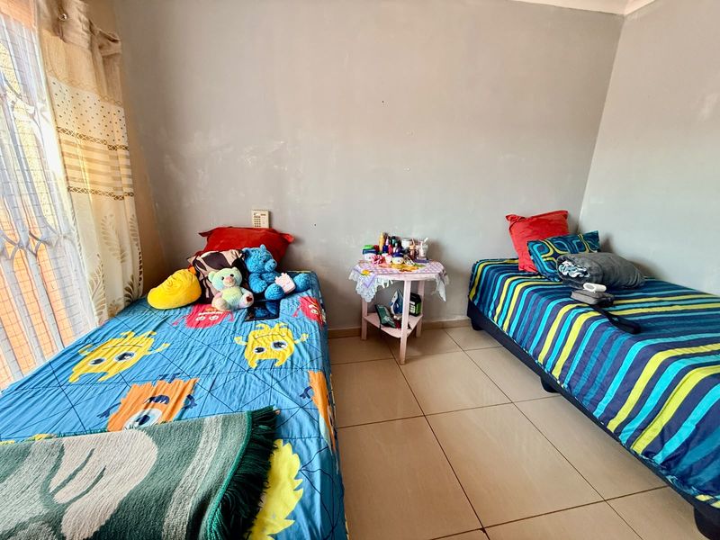 A bedroom featuring tiled flooring and a security gate on the window, requiring minor cosmetic updates to the wall finishes.