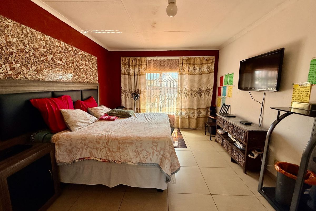 A bedroom featuring tiled flooring, a security gate at the window, and a built-in headboard with decorative stone wall cladding.