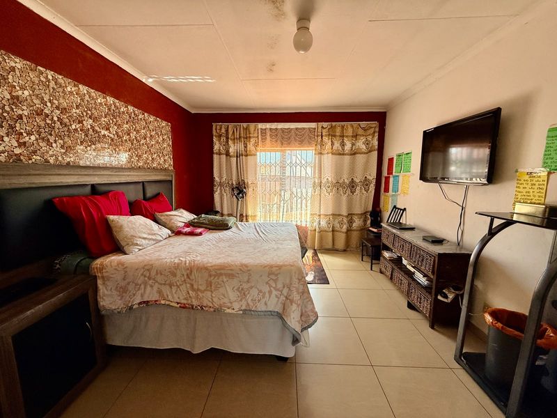 A bedroom featuring tiled flooring, a security gate at the window, and a built-in headboard with decorative stone wall cladding.