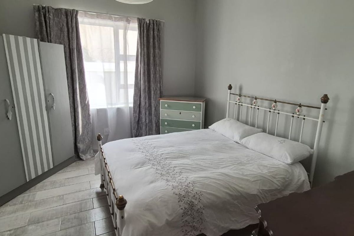 A bedroom featuring tiled flooring and a window, providing a functional space with neutral wall finishes.