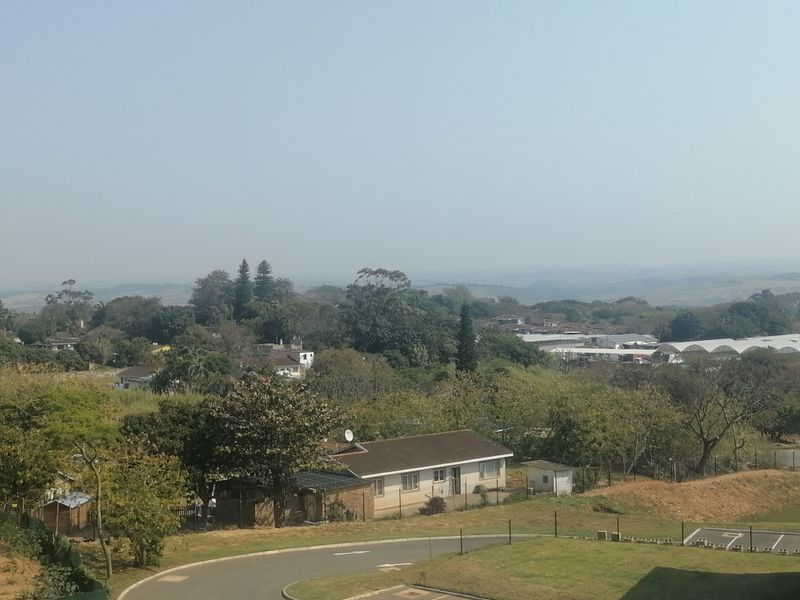 An elevated view overlooking the surrounding neighbourhood, green landscape, and distant hills.