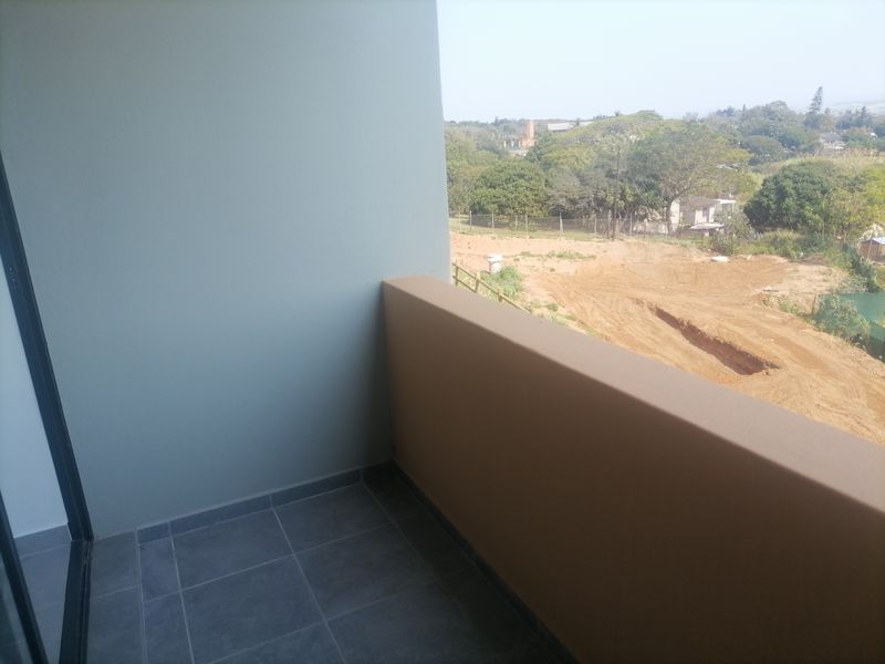 A clean, modern balcony featuring tiled flooring and a solid balustrade, offering an open view of the surrounding landscape.
