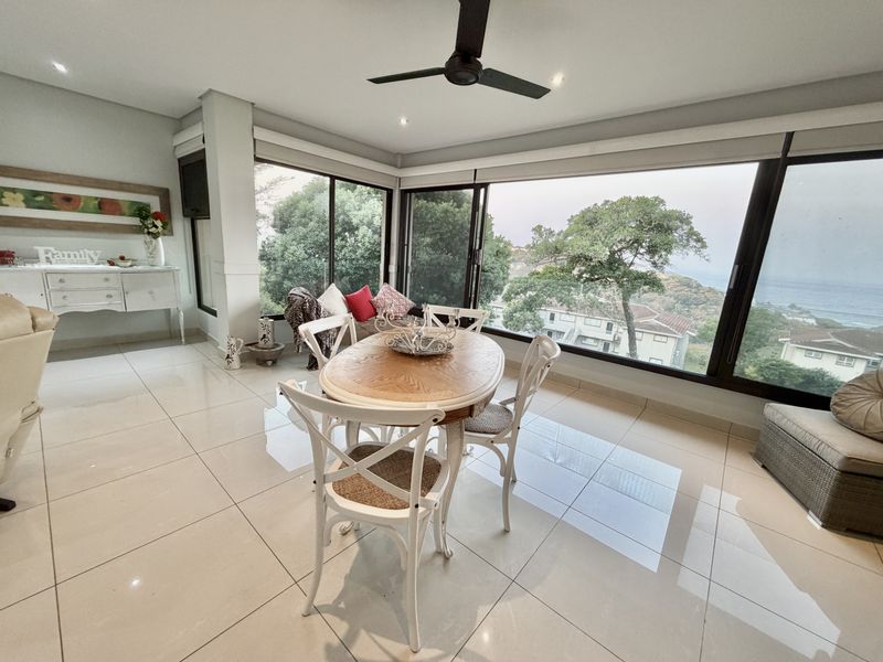 Bright dining area featuring large sliding glass doors with scenic views, tiled flooring, recessed lighting, and a ceiling fan.